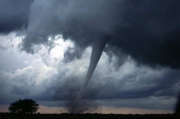 A tornado funnel cloud touching down in a field